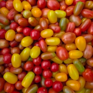 Tomates cherry surtidos rojos, amarillos y verdes, apilados en primer plano, listos para ensalada o cocina